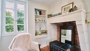 A room with a fireplace, a window, a bookshelf, and a chair.