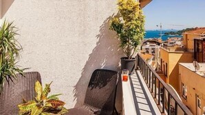A balcony with wicker furniture, a potted plant, and a clear view of the sea and buildings. - Stories Of Galata (İstanbul)