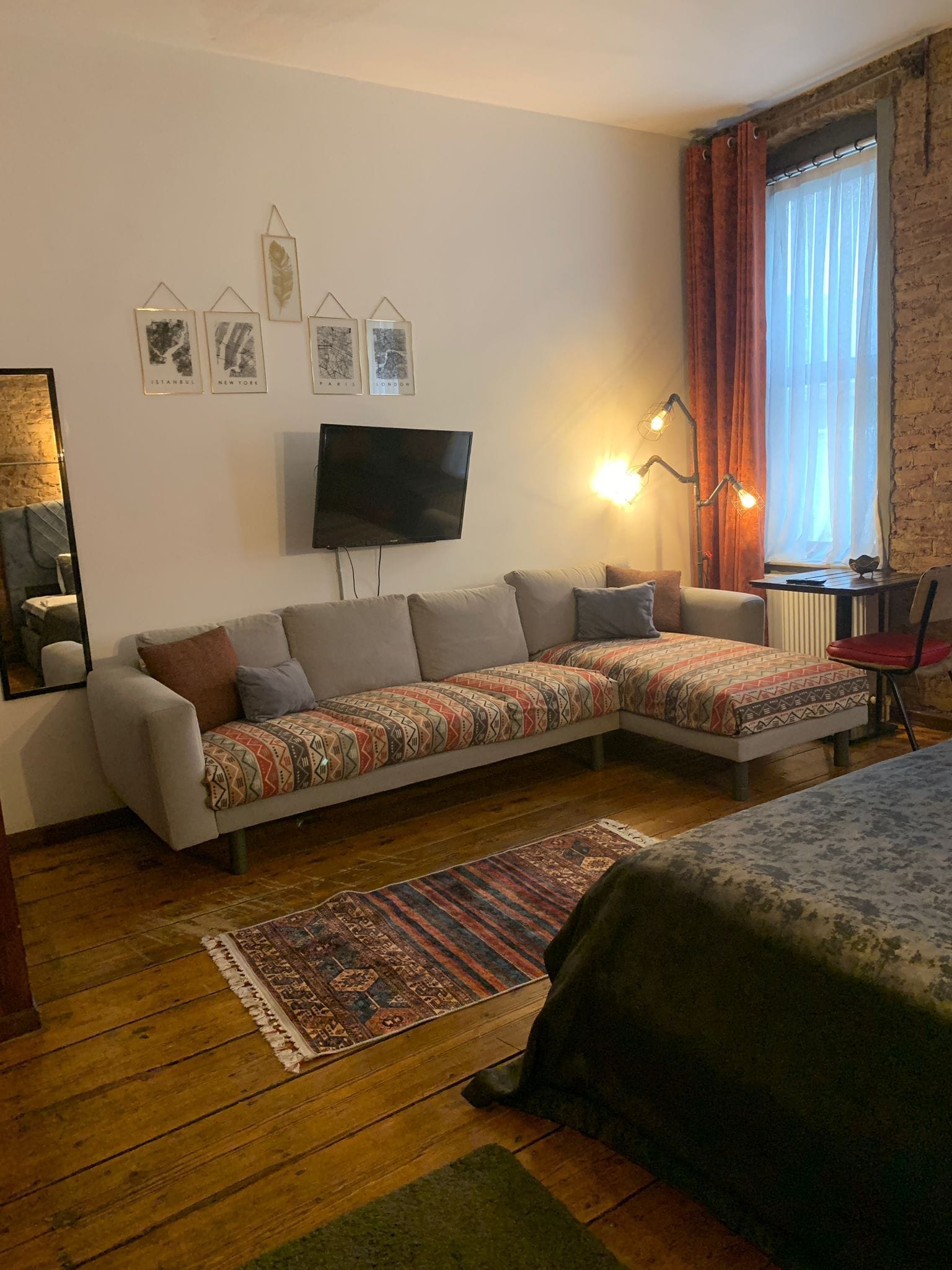A modern living room with a sofa, a TV, and a patterned rug.