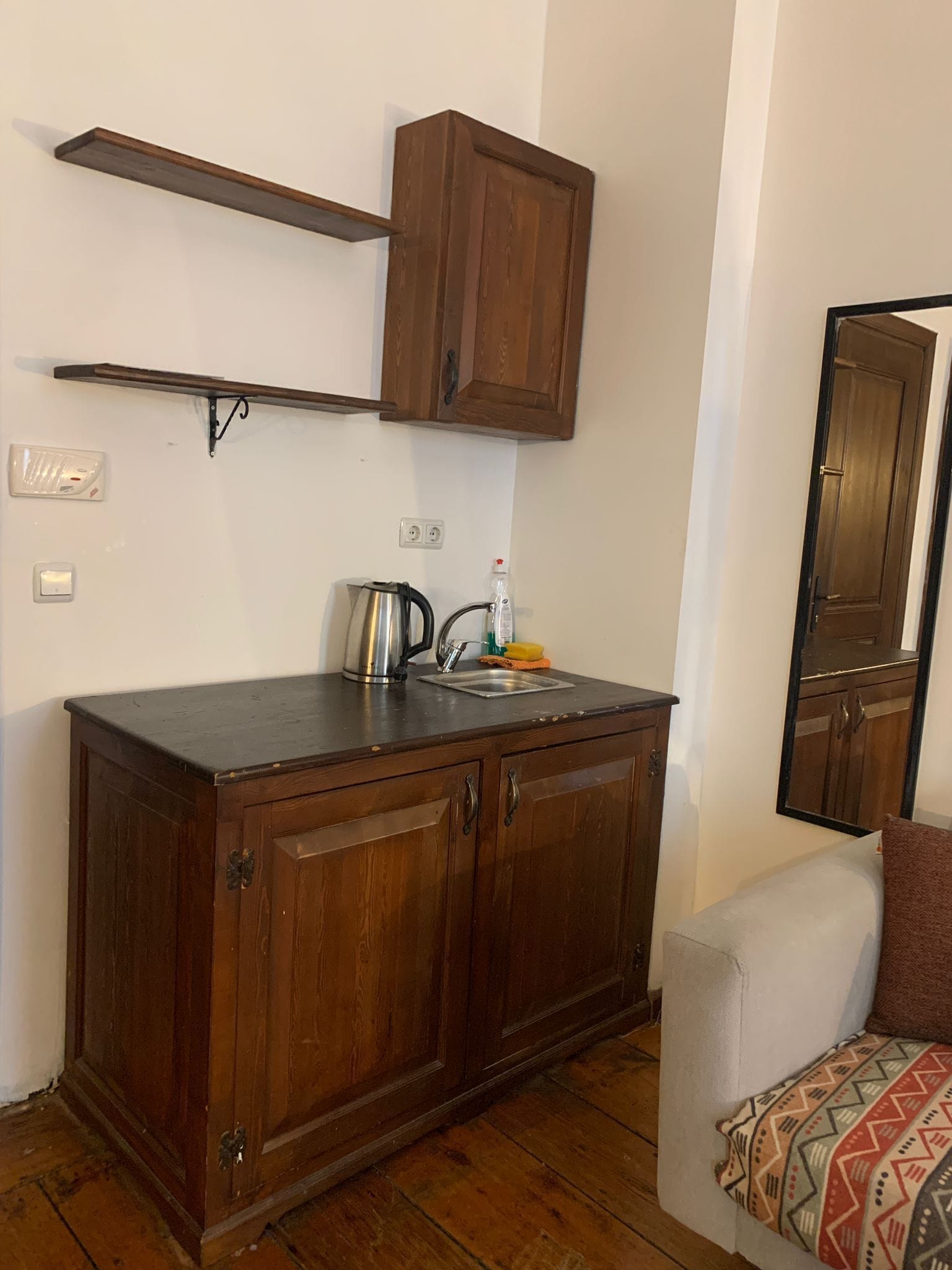 Cocina pequeña con armarios de madera, una encimera, un hervidor y un lavamanos.