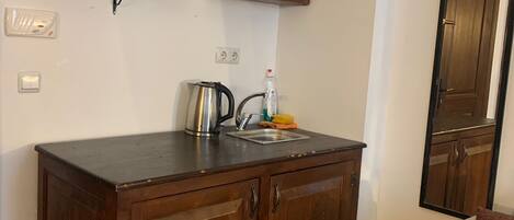 Cocina pequeña con armarios de madera, una encimera, un hervidor y un lavamanos.