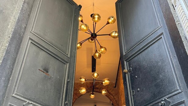 A narrow hallway with a decorative ceiling light fixture and a wall-mounted clock. - Stories Of Galata (İstanbul)