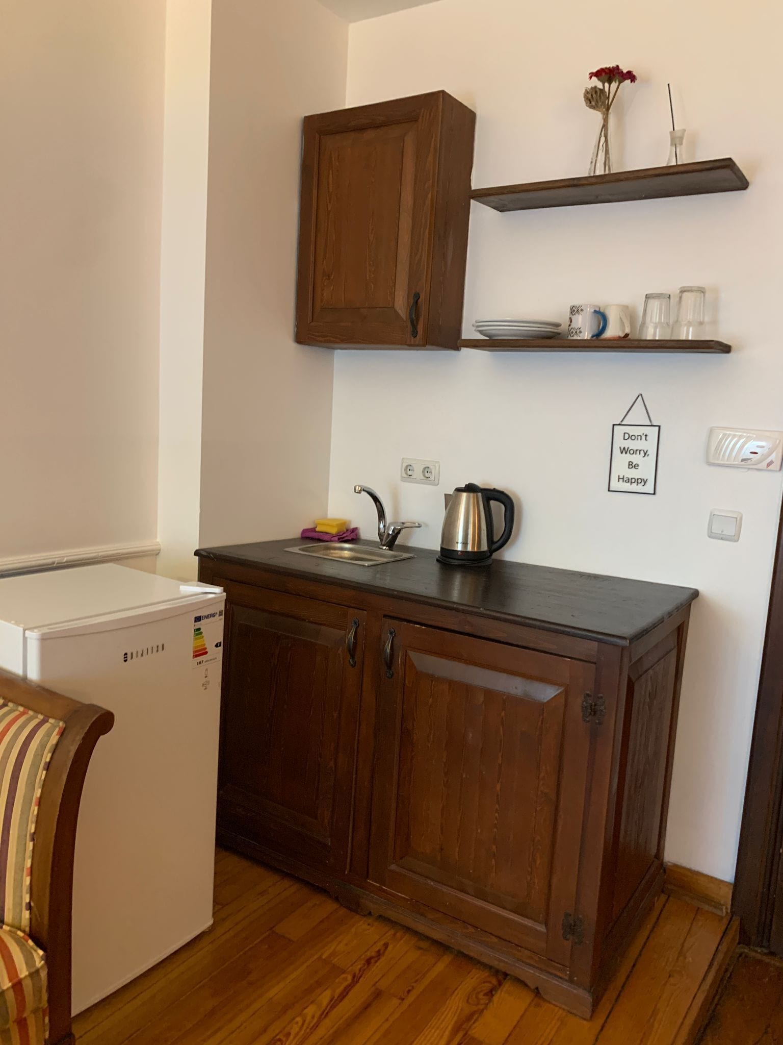 Una cocina compacta con armarios de madera, un refrigerador empotrado y una tetera sobre la encimera.