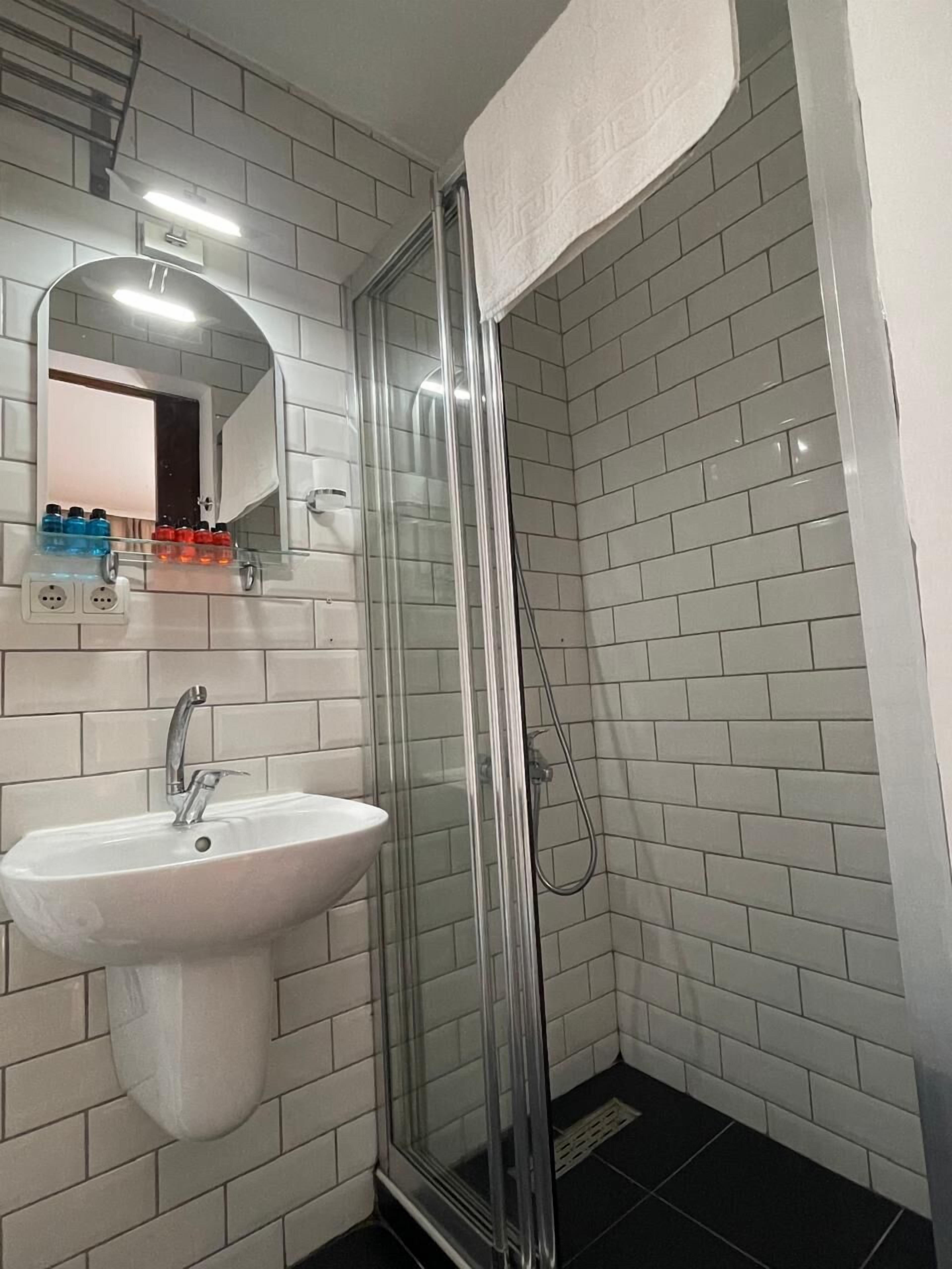 Een badkamer met een douche met glazen wanden, een witte wastafel en een spiegel erboven.