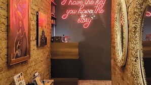 A narrow hallway with a brick wall, a neon sign, a reception desk, and patterned floor tiles. - Stories Of Galata (İstanbul)