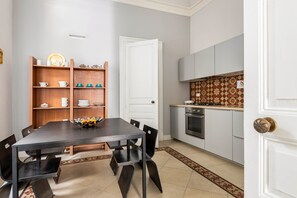A compact kitchen with a dining area, a white door, and a patterned backsplash.