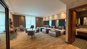A modern hotel room with a large bed, a sofa, a dining table, and a separate bathroom area. - ALSANCAK PRIME HOTEL KONYA  (Konya)