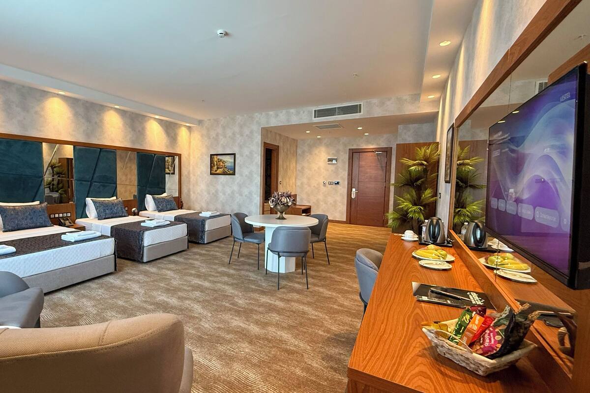 Una habitación de hotel moderna con una cama grande, un sofá, un comedor y un televisor.
