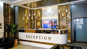 A reception area with a modern design, featuring a reception desk, a television, and various decorative items. - ALSANCAK PRIME HOTEL KONYA  (Konya)
