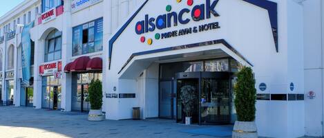 Un hotel con fachada moderna, un logotipo destacado y una entrada despejada.