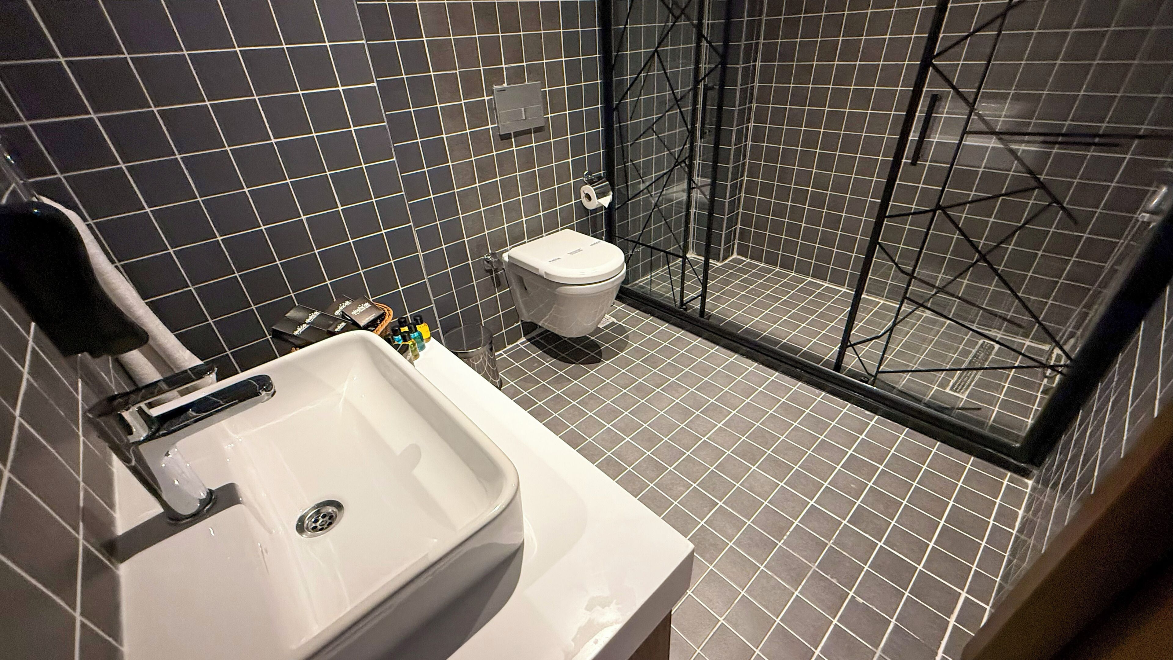 Un baño moderno con lavamanos, inodoro y cabina de ducha de vidrio.