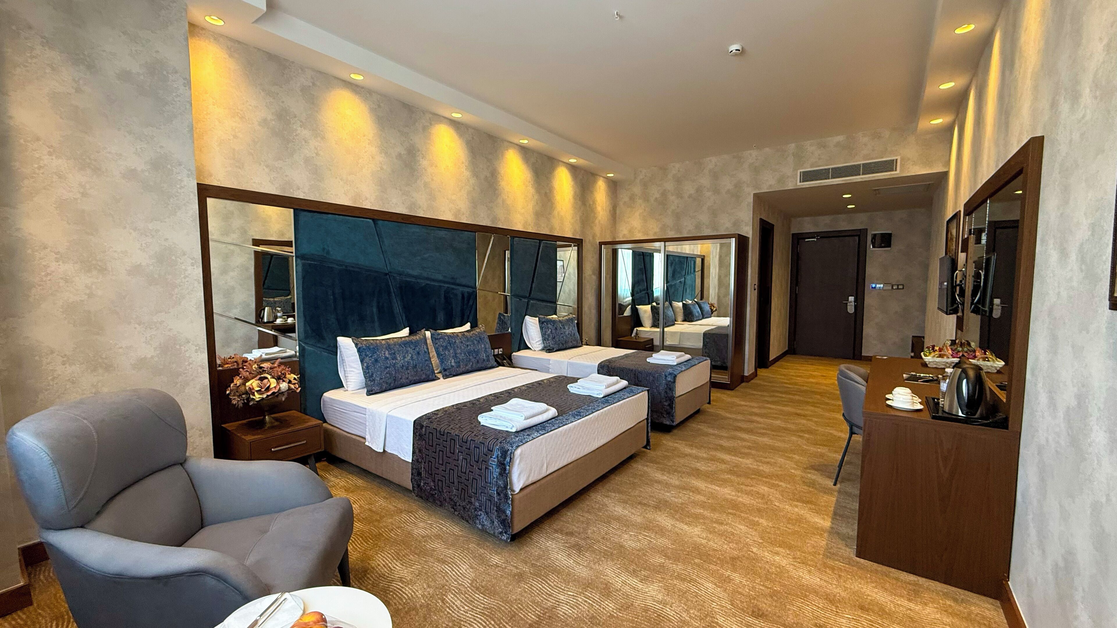 Ein Hotelzimmer mit zwei Betten, einem Schreibtisch, einem Stuhl und einem großen Spiegel.