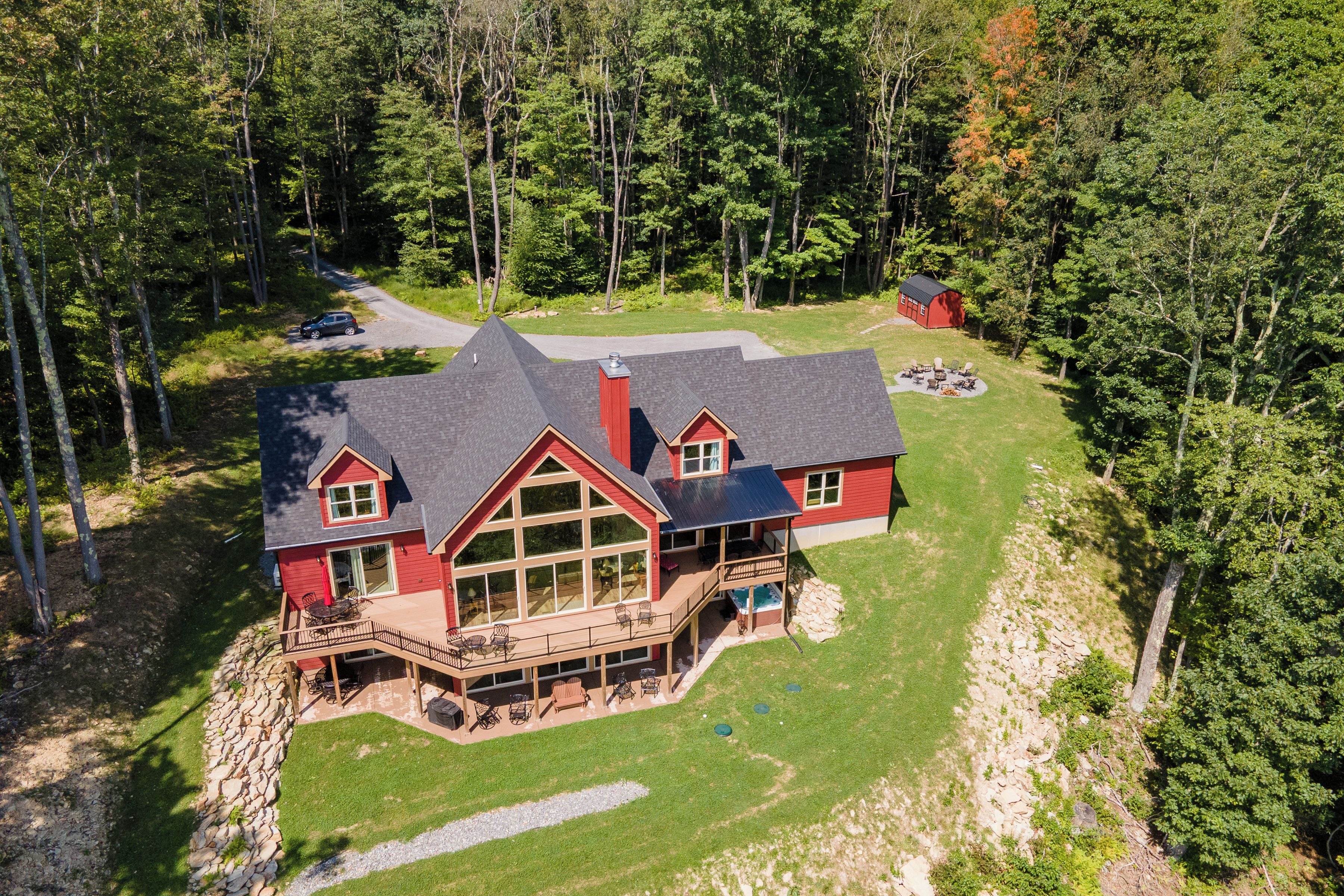 A large, two-story house with a deck, a hot tub, and a covered outdoor seating area.