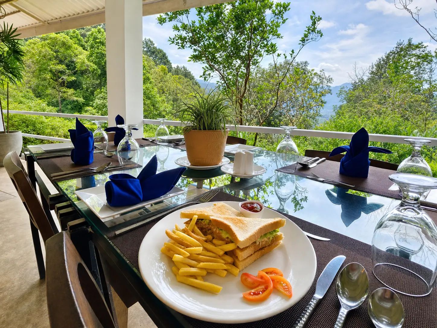 Een eettafel buiten, met uitzicht op groen en bergen, een bord eten en bestek.