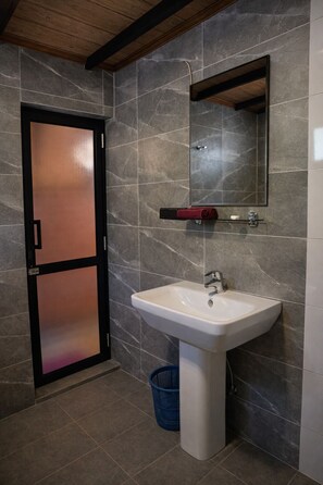 A bathroom with a white sink, a mirror, and a towel rack. - Forest Edge Hotel (Ginigathhena)