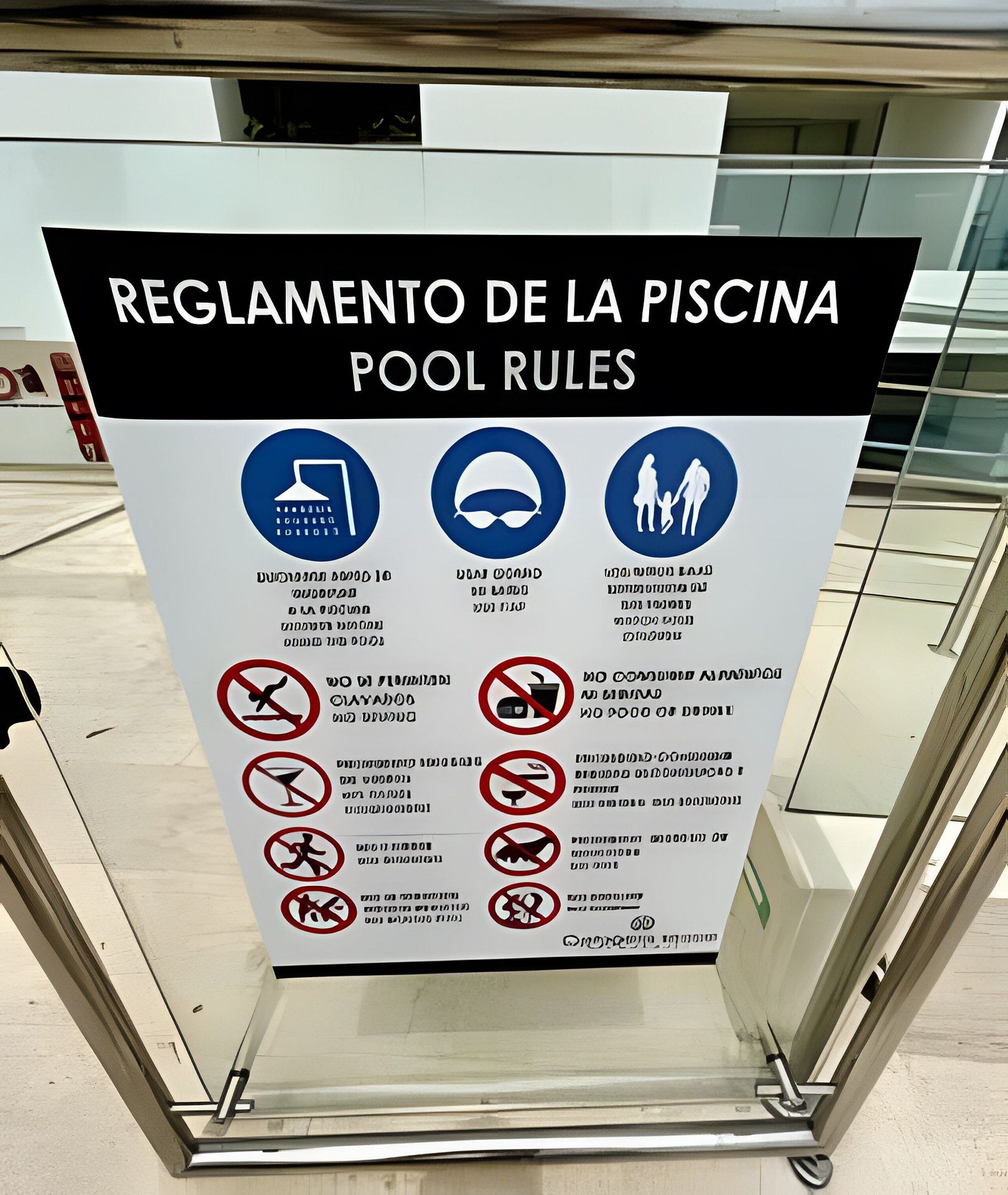 A sign with pool rules in Spanish, including symbols for no diving, no swimming, no running, no diving, no diving, no diving, no diving, no diving, no diving, no diving, no diving, no diving, no diving, no diving, no diving, no diving, no diving, no diving, no diving, no diving, no diving, no diving, no diving, no diving, no diving, no diving, no diving, no diving, no diving, no diving, no diving, no diving, no diving, no diving, no diving, no diving, no diving, no diving, no diving, no diving, no diving, no diving, no diving, no diving, no diving, no diving, no diving, no diving, no diving, no diving, no diving, no diving, no diving, no diving, no diving, no diving, no diving, no diving, no diving, no diving, no diving, no diving,