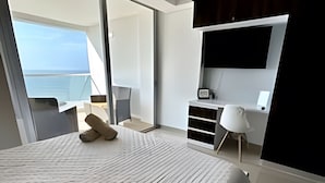 A modern hotel room with a large bed, a desk, a chair, and a TV mounted on the wall. - 1404 Suite Frente al Mar en Cartagena (Cartagena)