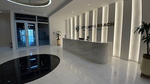 A modern reception area with a marble counter, a large potted plant, and a sign reading "Cartagena Beach Exclusive Residences." - 1404 Suite Frente al Mar en Cartagena (Cartagena)