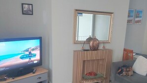 Un salon avec une télévision, une cheminée, un canapé et une petite table.