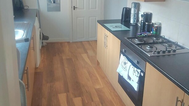 Une cuisine de taille réduite, dotée de meubles en bois, d’une cuisinière et d’un lave-vaisselle.