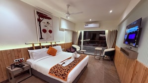 A hotel room with a bed, a TV, a desk, and a window with curtains. - Ikonic Hotel - Bhushi Dam Lonavala (Lonavala)