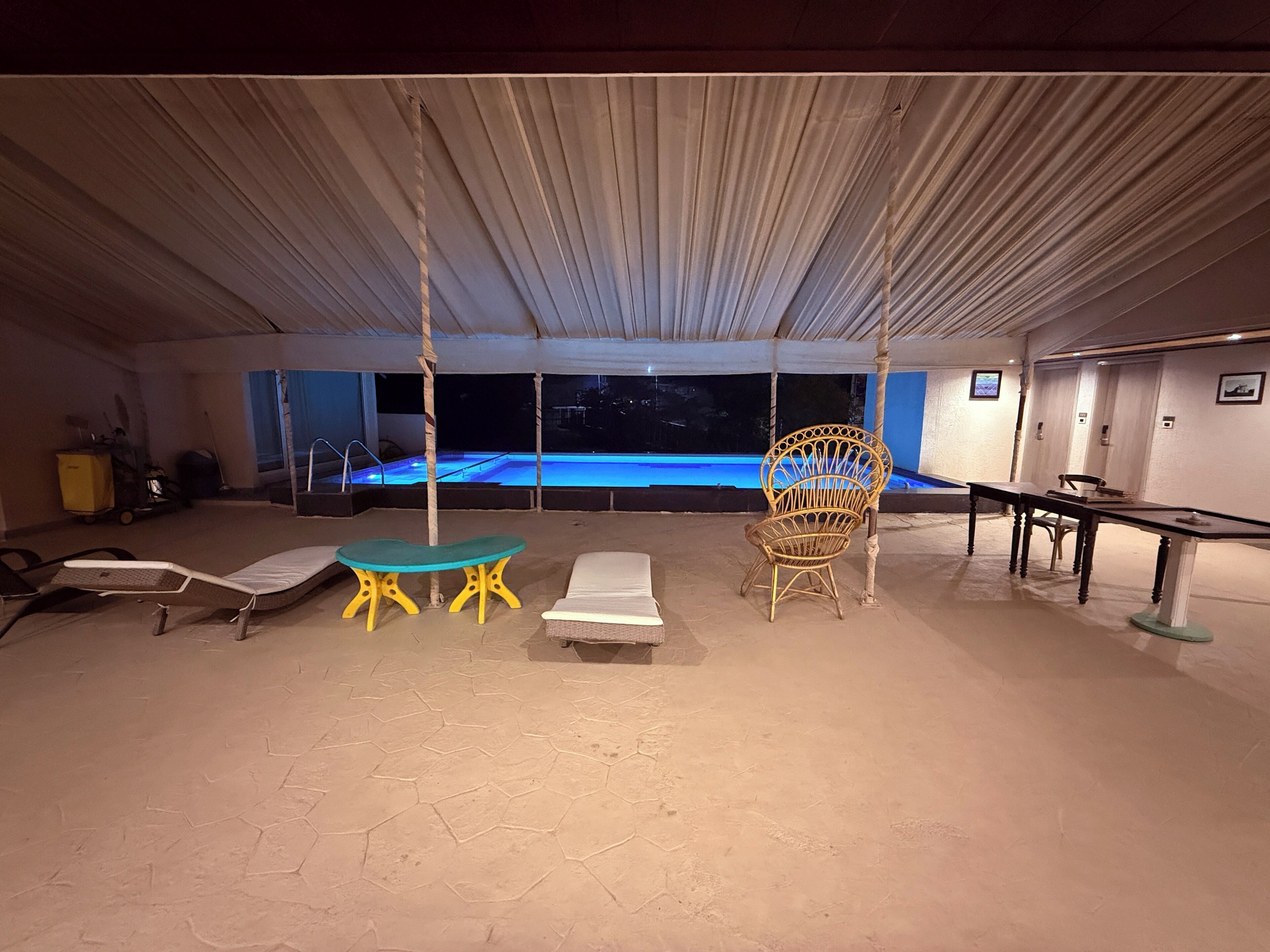 Ein Zimmer mit Pool, Liegestühlen, einem Tisch und einer Hängematte.