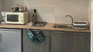 A modern kitchen with a microwave, stove, sink, and wooden cabinets. - Super apartment with free parking (Saint-Étienne)