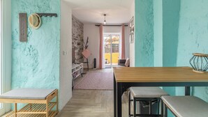 Una habitación con paredes verde agua, una mesa de madera, un banco y un sombrero en la pared.