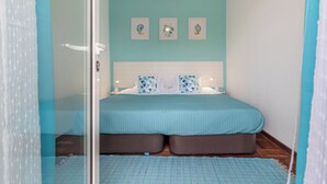 Un dormitorio con una cama, una mesita de noche y una pared decorada con tres cuadros.