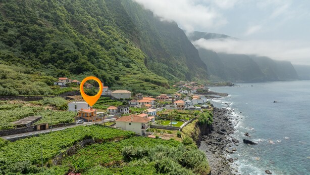 Un pueblo costero con casas a lo largo del mar, rodeado de exuberante vegetación y montañas.