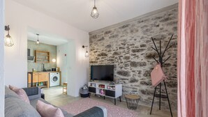 Una sala moderna con un sofá gris, un televisor y una pared de piedra.