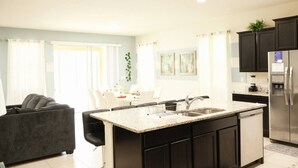 A modern kitchen with dark cabinetry, a stainless steel refrigerator, and a granite countertop.