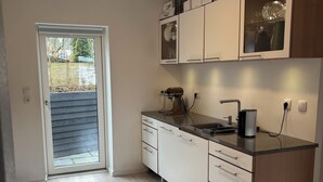 Una cocina moderna con piso de madera clara, armarios blancos y horno empotrado.