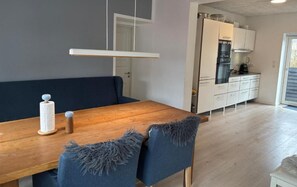 Moderni keittiö, jossa on valkoiset kaapit ja puinen työtaso.