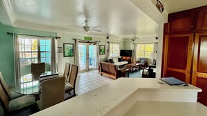 A spacious living area with a dining table, chairs, a sofa, a TV, and a ceiling fan. - Sunset Beach Resort (San Pedro)