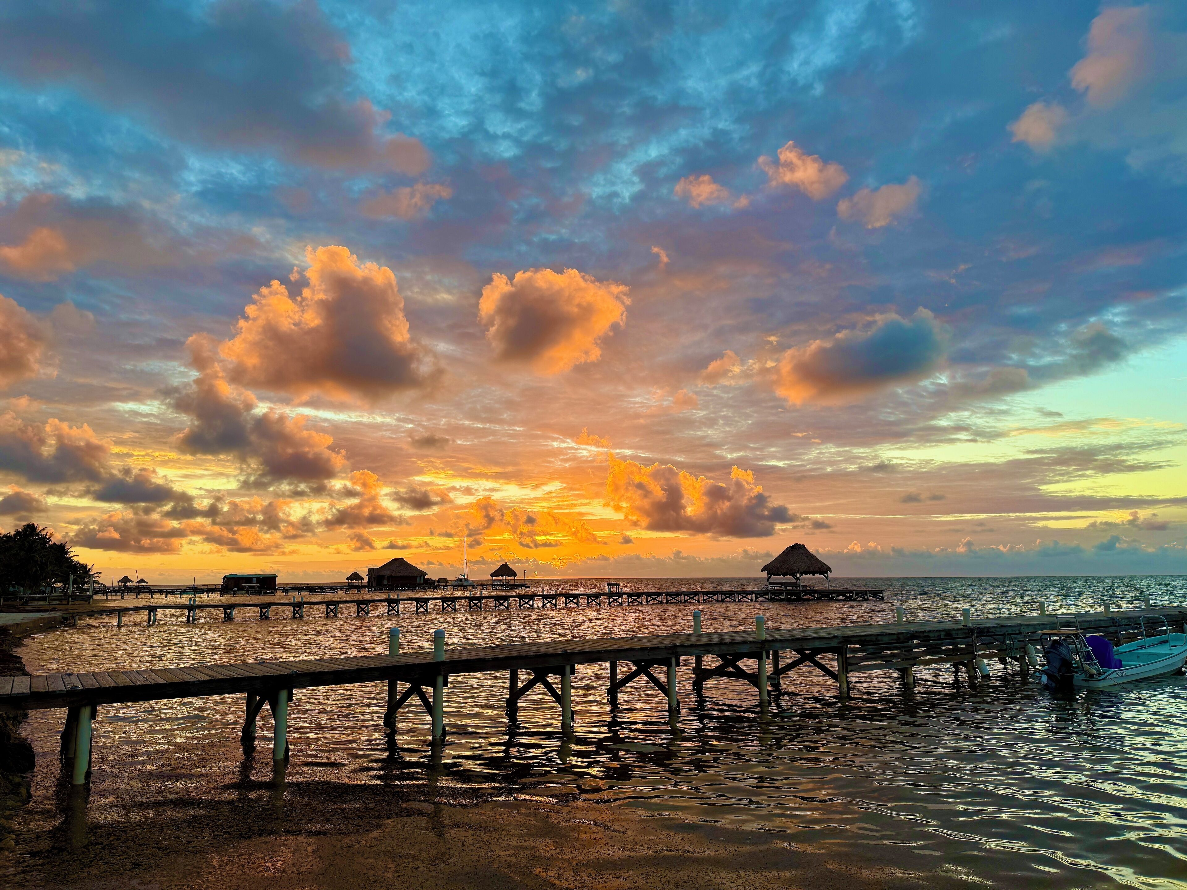 Eine Steg, der sich in ruhiges Wasser erstreckt, mit überhängenden Bauwerken und einem Sonnenuntergangshimmel.