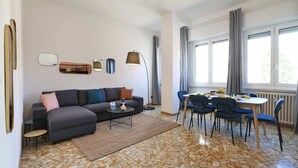 A modern living room with a sofa, coffee table, and dining area with chairs. - Sweett | Fontana - Two Bedroom Apartment, Sleeps 5 (Milano)