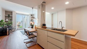 A modern kitchen with a wooden countertop, stainless steel sink, and a dining area with a table and chairs. - Sweett | Luxury Velasca IV (Milano)