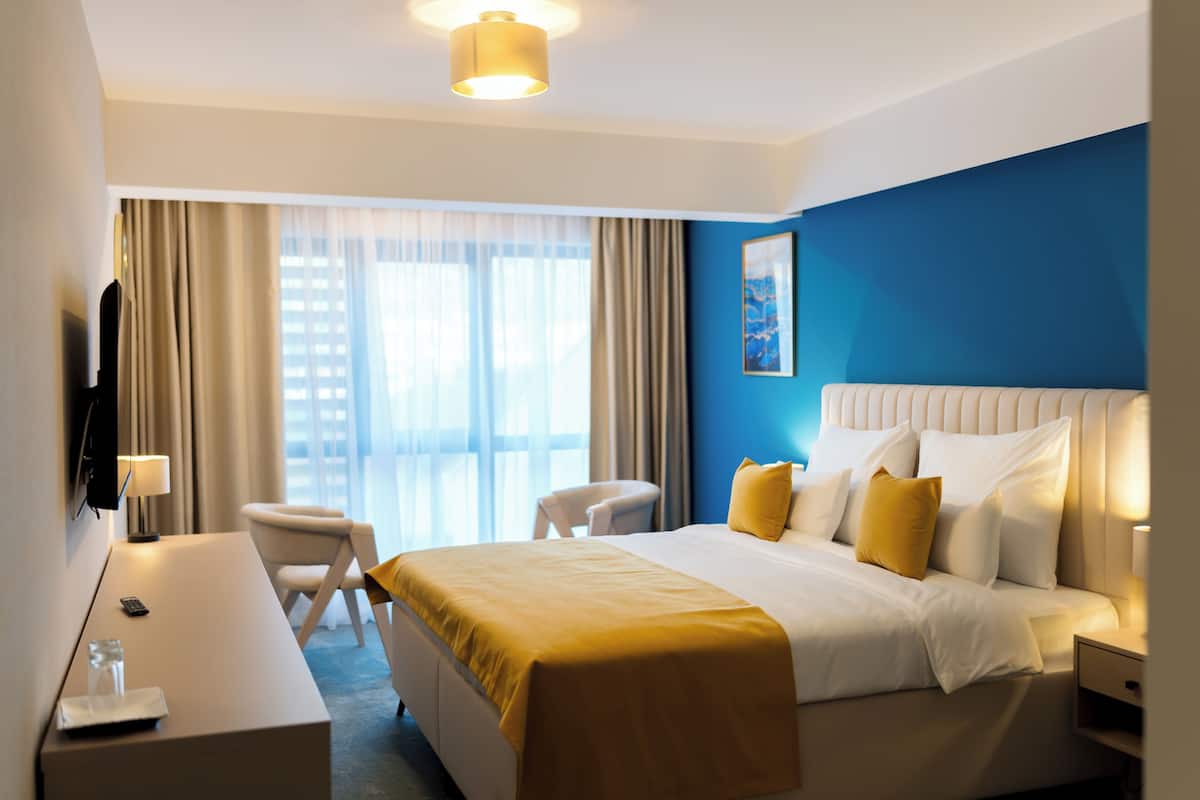 Une chambre d’hôtel avec un lit, un bureau, une chaise et un téléviseur.