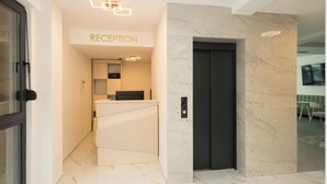 A reception area with a marble wall, a reception desk, and a door.