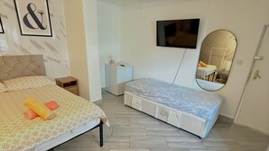 A bedroom with a bed, a small bedside table, a TV, a mirror, and a wardrobe.