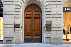 Een grote houten dubbele deur met een metalen drempel, omlijst door twee plaquettes en een codeerapparaat.