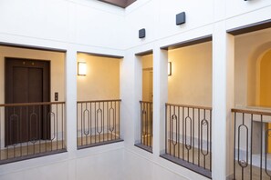 A modern interior with a white wall, a wooden door, and a metal railing.