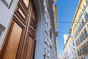 A narrow street with historic buildings, including a building with a large wooden door and another with a sign that reads "HOTEL CALLE."