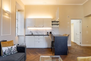 A modern kitchen with white cabinets, a marble countertop, and a bar area.
