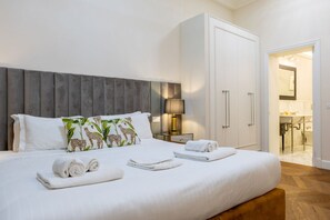 A neatly made bed with rolled towels, a bedside lamp, and a wardrobe in a hotel room. - Calzaiuoli Private House Silver (Firenze)
