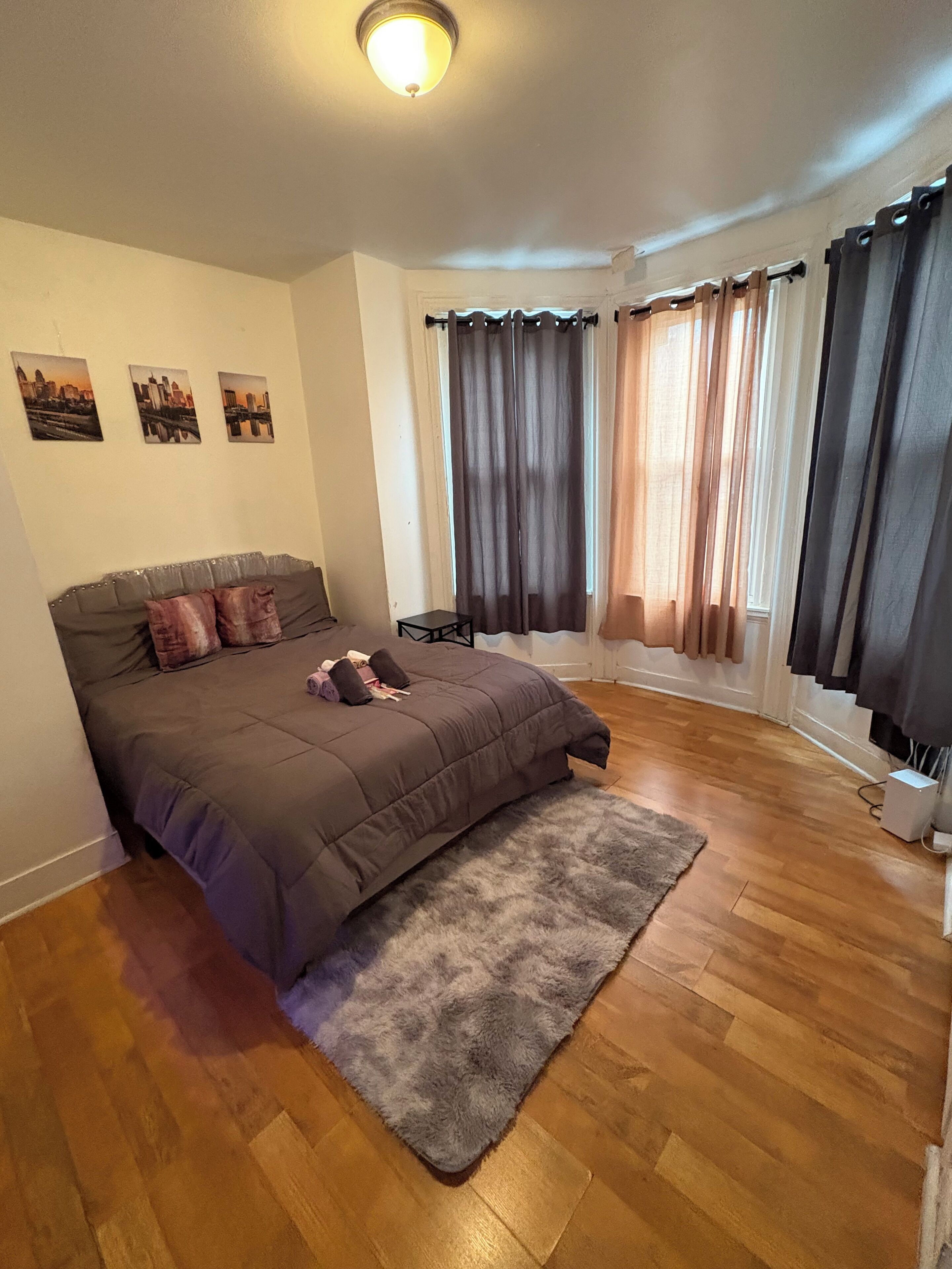 Une chambre à coucher avec un lit, un tapis, une petite table et des rideaux.