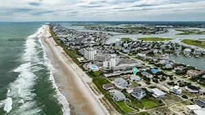 Luchtbeeld van een kustplaats met een strand, woonwijken en een jachthaven.