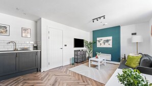 A modern kitchen with grey cabinets, a white countertop, and a herringbone wood floor. - Boho Vista| Stylish Central1BR Flat in Cardiff Bay (Cardiff)