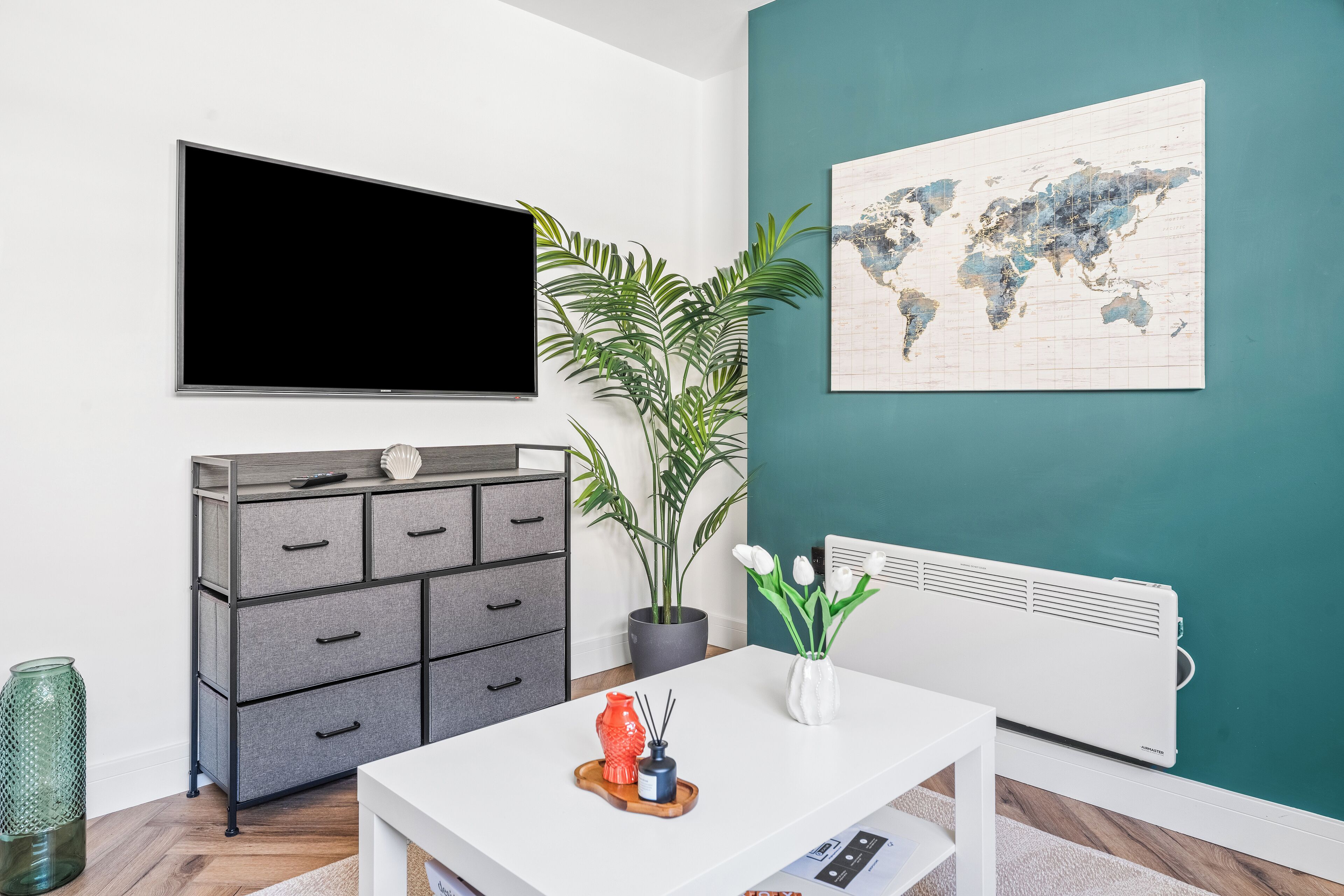 A modern living room with a grey cabinet, a large world map on the wall, a potted plant, and a white radiator.